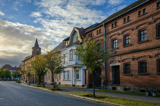 Denkmalgesch&uuml;tzte H&auml;userzeile in Beeskow mit Blick auf den Turm der Pfarrkirche St. Marien im Morgenlicht - Graffiti-Schmierereien wurden retuschiert