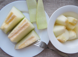 Cut open cantaloupe melon , sweet melon with seeds close up  , Slices of juicy and tasty melon on a white plate. Top viewOrganic summer natural background Photo