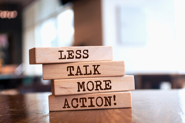 Wooden blocks with words 'Less Talk More Action'.