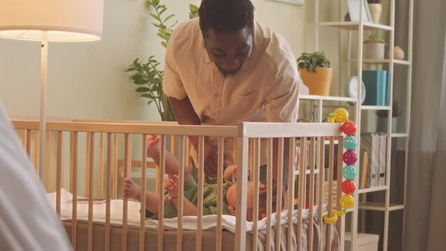 African American man putting his cute baby son to sleep at home at daytime