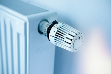 White panel radiator with a modern thermostat on the wall in an apartment - selective focus
