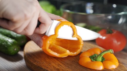 Chef slicing fresh vegetables in the kitchen. Man hand cutting orange, big, fresh pepper in the kitchen.