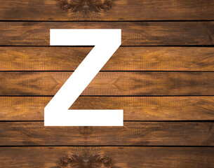 Z capital letter of alphabet in white hole on wood background