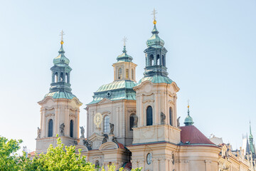 Fototapeta na wymiar Saint Nicholas Church with bell towers near the castle and Saint Vitus Cathedral in Prague historical downtown, Czech Republic, at blue sky and sunny day.