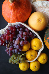 Various healthy autumnal food in reusable mesh bags. Top view, dark background.