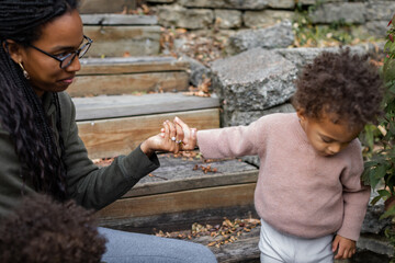 Biracial mother hold son's hand in backyard in fall 