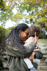 Black mother hugging toddler boy and smiling in fall 