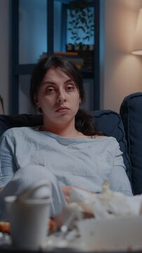 Vertical video: Portrait of traumatised, frustrated stressed depressed woman looking in distance sitting alone on couch feeling emotionally unstable, lonely desperate, vulnerable suffering from
