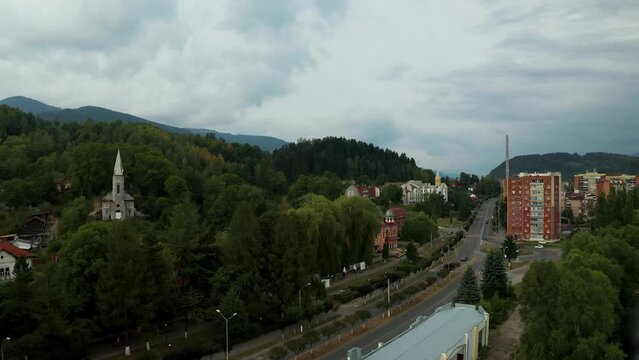 Aerial top-down 4k view over a small Romanian town, in the area of Hunedoara. Cinematic drone shot flying over a gravel road in pine trees in Lupeni town surrounded by mountains. Aerial view, Lupeni, 