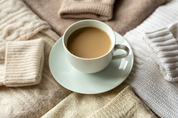 A mug of cocoa among beige sweaters, autumn mood