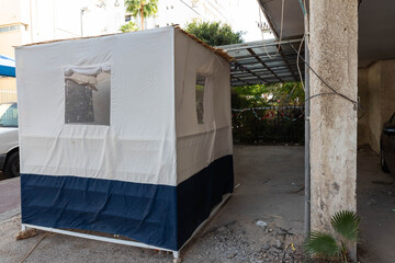 Jewish festival of Sukkot in Israel. Traditional sukkah with handmade decorations near the building on the street. 