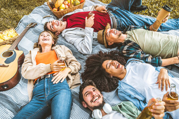 Friends group having fun together lying on the grass - Young people having picnic camping outdoor -...