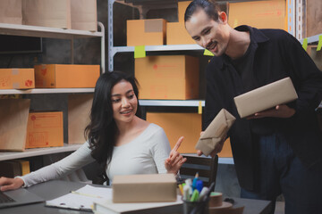 SME entrepreneur business woman is pointing at parcel box while her co-worker holding a box. ...