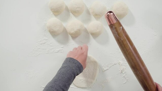 Flat lay. Rolling bread dough with a french rolling pin to make homemade flatbread.