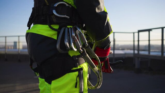 Close-up of an industrial climber unfastens the trigger device from the loop of the safety system and jumps to the bottom point