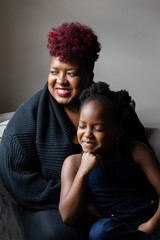 Obraz premium African American mother and daughter smiling and looking out window
