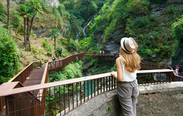 Girl on the path into the wild enjoying landscape with waterfalls and the gorges of a natural canyon