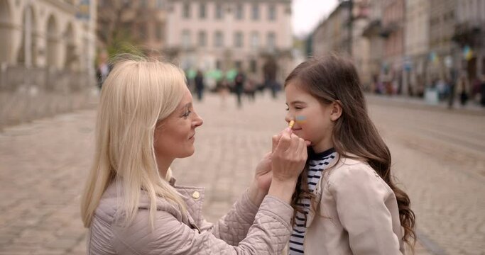 Ukrainian mother drawing a flag on daughter's face