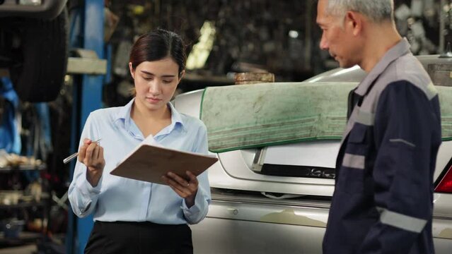 Accident Inspector Inspect damage car caused by car crash on the road. Asian man Car insurance agent and woman customer examining white car by digital tablet in garage.