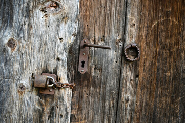 Old Door handle, close up. Ancient rusty door handle and keylock on brown old wooden door. House gate.