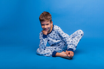 a little boy is sitting in pajamas on a blue background. the concept of healthy sleep. pajamas made...
