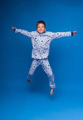 A happy child in pajamas jumps on an isolated blue background. the concept of sleep. photos for wildberris