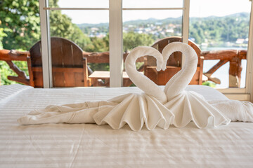 Folded couple swan towel on the bed in the hotel