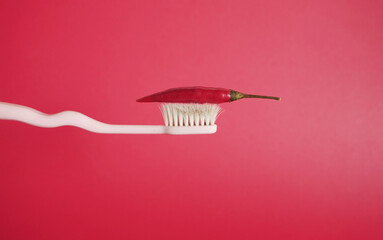 Red chili pepper on toothbrush with red background