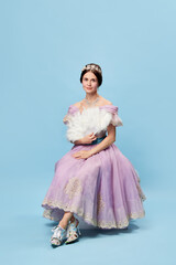 Stylishness. Beautiful charming girl in lilac color medieval dress as young queen or princess on blue background. Eras comparison, beauty, art © master1305