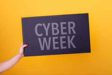 Female hand holding a cyber week poster. Studio shot. Commercial concept. - obrazy, fototapety, plakaty