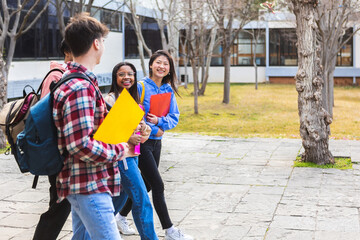Diverse group of teenage student friends walking after classes outside at high school - Education...