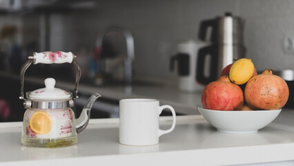 White Porcelain Mug Mockup. A single white sublimation printable empty mug in the modern kitchen with fresh fruits and hot lemon drinks.