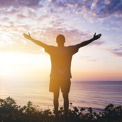 Fototapeta premium Man with arms outstretched celebrating in beautiful inspiring sunset