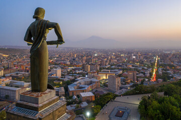 View of Mother Armenia Statue, Eternal Fire in Akhtanak Park and the city in the evening. Yerevan, Armenia.