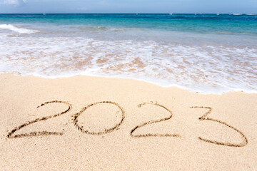 New Year 2023, lettering on the beach with wave