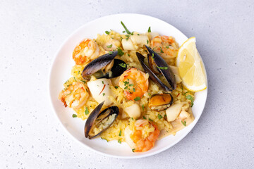 Seafood risotto with saffron, parsley and lemon. Arborio rice with tiger prawns, mussels and squid. Traditional Italian dish. Close-up, selective focus.