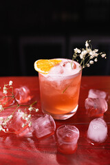 A glass with a red cocktail garnished with an orange slice in a nightclub bar. Night life, club life. Excellent serving of cocktails