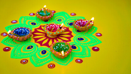 Oil lamps lit on colorful rangoli during diwali celebration. Happy Diwali - Clay Diya lamps lit...