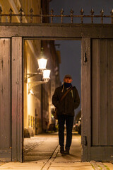 Copenhagen, Denmark  A man walks on a small street and gate in the Christianshavn district at night.