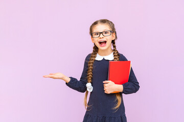 A schoolgirl holds notebooks and your advertisement on the palm of a pink isolated background. Educational courses for secondary school children.