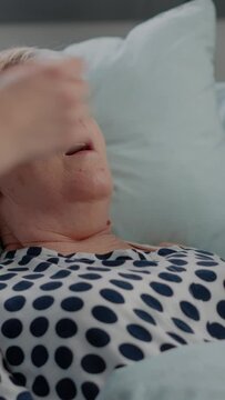 Vertical video: Close up of hyperventilating woman in hospital ward bed while doctor and nurse using oxygen tube for respiratory problem. Senior patient receiving help against breathing heavily.