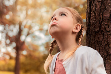 portrait of a little cute girl with pigtails among the leaves in the forest