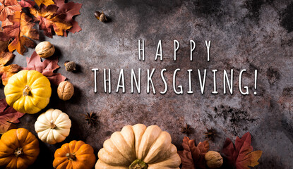 Thanksgiving background concept with fall leaves, pumpkin and seasonal autumnal decor on dark stone background with the text.