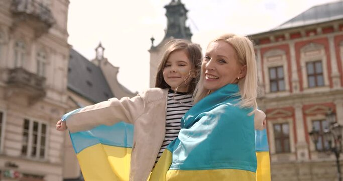 Ukrainian mother and daughter with national flags outdoors