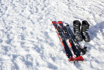 Mountain skis, ski boots and poles on bright alpine snow. Winter holidays. Extreme sport.  Vacation, travel content. Copy space