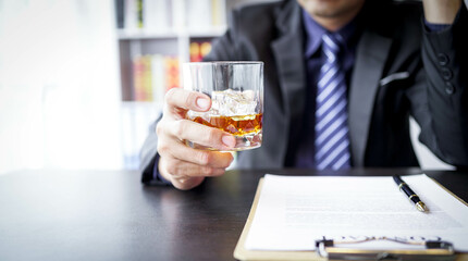 Glasses of whiskey in businessman's hands on wooden table background