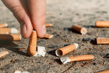 The man's hand extinguishes a lit cigarette. Cigarettes are harmful to health