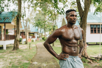 Black young sportsman resting while working out with jumping rope outdoors