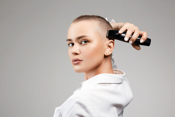 beautiful young woman cutting her hair. bald Girl with hairclipper