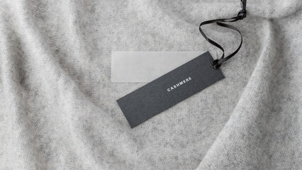 Dark paper tag with word cashmere on light grey luxury pure cashmere  background.